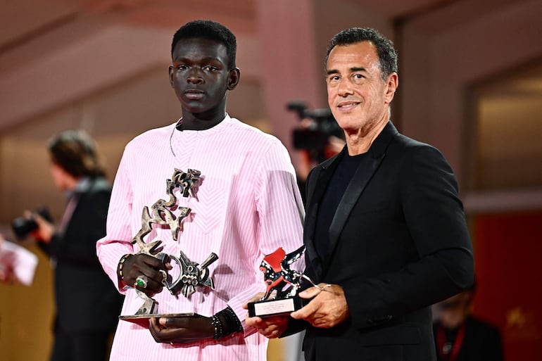 Seydou Sarr, ganador del premio "Marcello Mastroianni" al Mejor nuevo actor y el cineasta Matteo Garrone tras la premiación a "Io Capitano" en la Mostra.