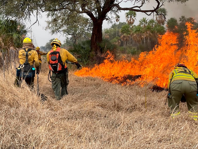 Bomberos intentan sofocar un incendio, el lunes en la zona de Fuerte Olimpo.