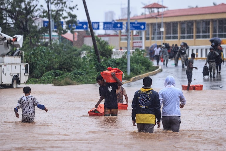 Personas cruzan una avenida inundada por el paso del huracán 'John' en la parte alta del puerto de Acapulco, este viernes, en Guerrero (México). 