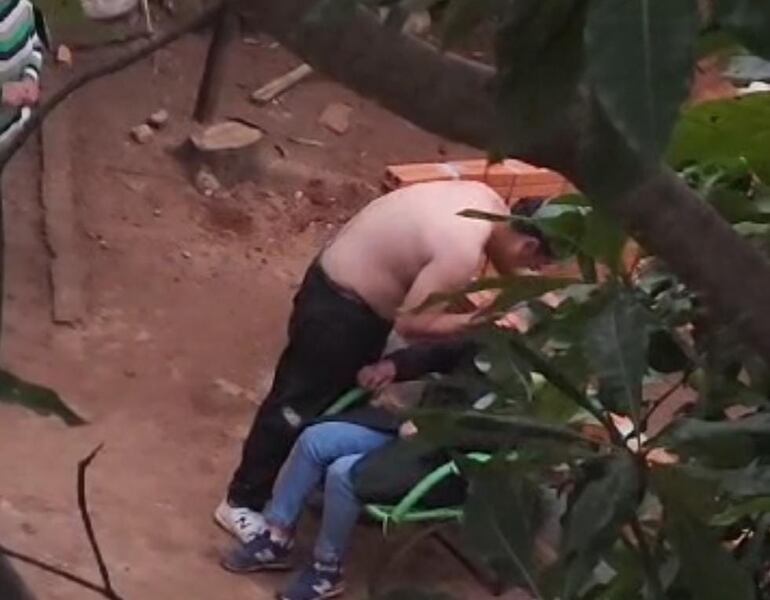 Captura de pantalla del momento en que el hombre golpea la cabeza de la mujer contra una pared en construcción.