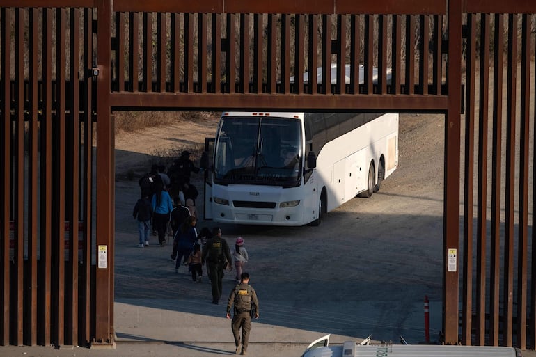 Migrantes en el muro fronterizo entre México y los Estados Unidos entre San Diego y Tijuana.