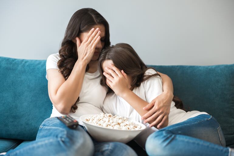 Madre e hija evitan mirar escena violenta en una película.