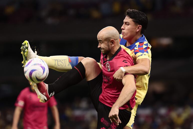 AME4423. CIUDAD DE MÉXICO (MÉXICO), 04/11/2023.- Ramón Juárez (d) de América disputa el balón con Carlos González de Tjuana, durante un partido de la jornada 16 del Torneo Apertura del fútbol mexicano disputado en el Estadio Azteca, en Ciudad de México (México). EFE/José Méndez