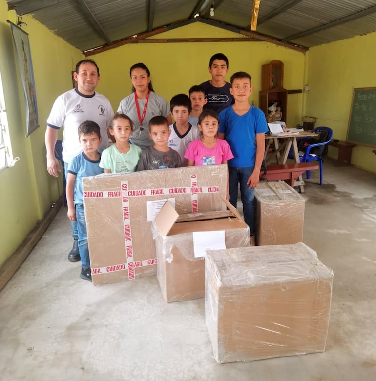 El maestro con sus alumnitos y las cajas de regalos que recibieron de parte de la ciudadanía.