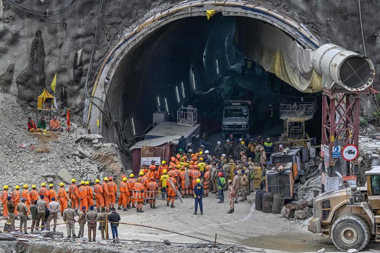 El personal de la Fuerza Nacional de Respuesta a Desastres (NDRF) junto con otros operativos de rescate se reúnen cerca de la cara del túnel Silkyara en construcción colapsado en el distrito de Uttarkashi del estado indio de Uttarakhand, el 28 de noviembre de 2023. Los equipos de rescate indios que excavan a mano están abriéndose paso para llegar a 41 hombres atrapados en un túnel de carretera derrumbado.