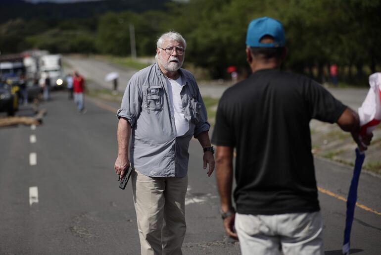 Un hombre sostiene un arma frente a un manifestante en medio de un bloqueo de docentes en la vía Panamericana, en Chame (Panamá).