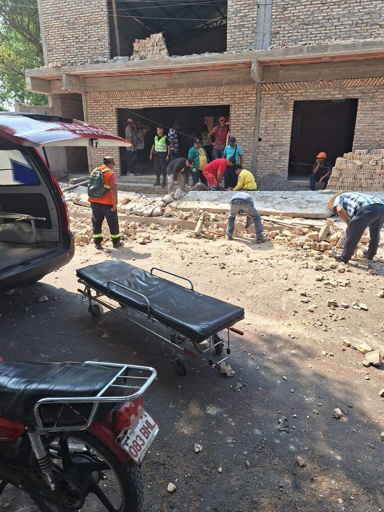 Bomberos voluntarios trabajan para rescatar al albañil, Miguel Angel Melgarejo, atrapado bajo los escombros, tras el derrumbe de una parte de la estructura del futuro edificio de la empresa recolectora, Nuevo Horizonte.