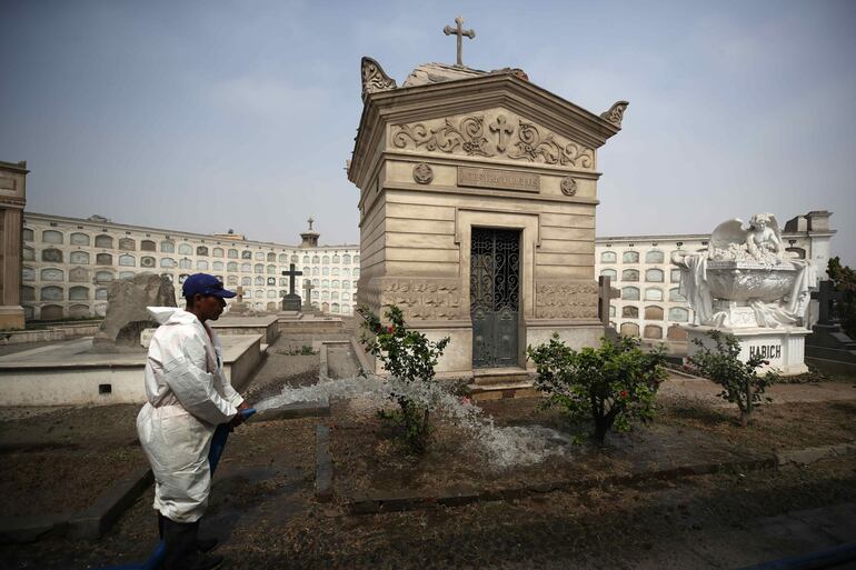 Un trabajador riega las plantas al interior del Cementerio General de Lima Presbítero Maestro, en Lima (Perú).  