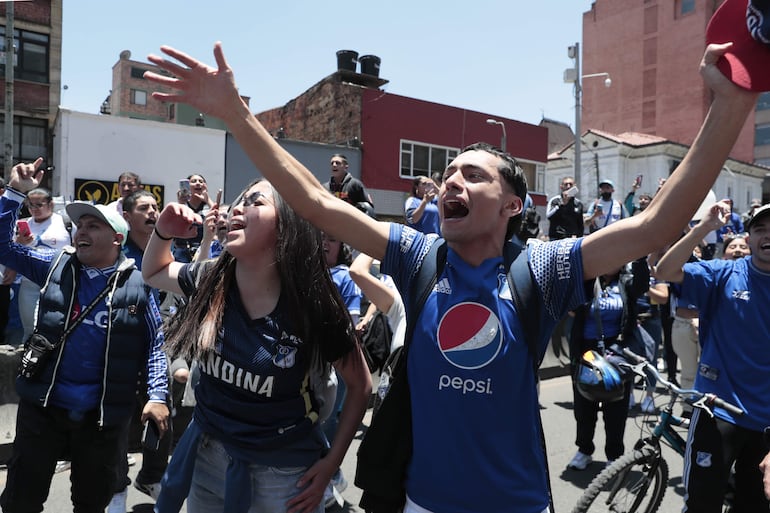 Integrantes de la barra Comandos Azules del equipo colombiano Millonarios alientan afuera del hospital San Ignacio para despedir a Javier Acosta este viernes, en Bogotá (Colombia). 