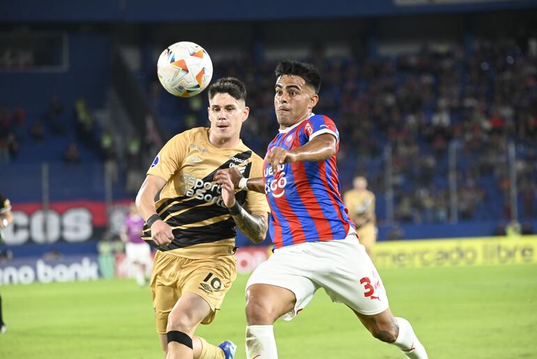 El defensor de Cerro Porteño, Miguel Benítez pelea por el balón con el volante del Athletico Paranaense Bruno Zapelli