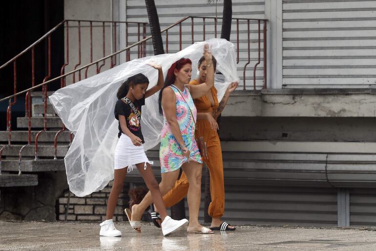 Imagen de archivo de tres mujeres caminando durante una tormenta.