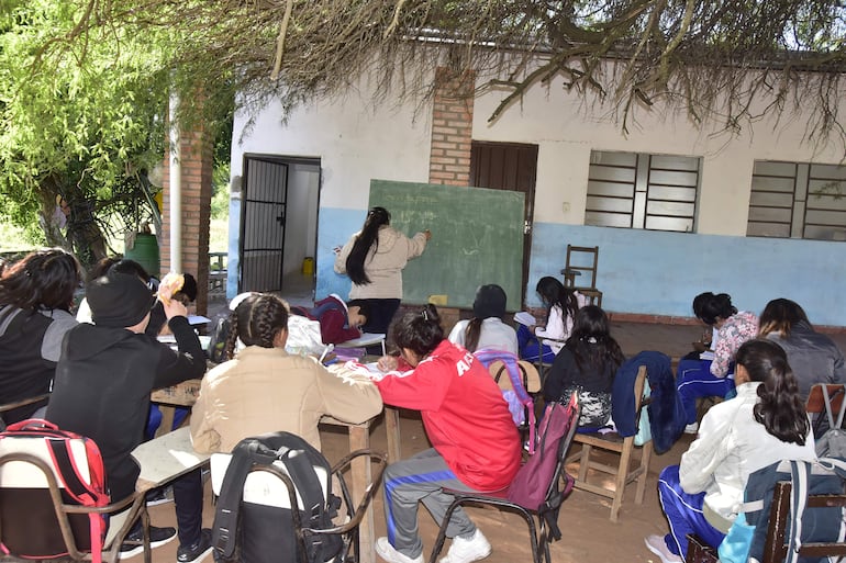 Profesora da clases en una pizarra prestada ante la atenta mirada de los estudiantes del noveno grado, en otro rincón de la escuela Nueva Esperanza, en Chaco´i.