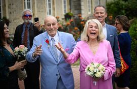El veterano estadounidense de la Segunda Guerra Mundial Harold Terens, de 100 años (izq.), y Jeanne Swerlin, de 96 años, (derecha), hacen un gesto de alegría cuando llegan a su boda en el ayuntamiento de Carentan-les-Marais, en Normandía, noroeste de Francia.