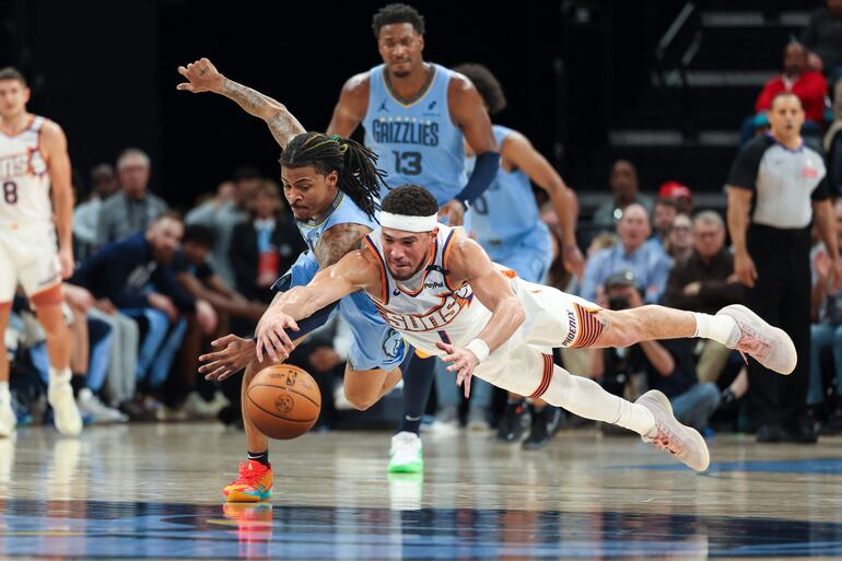 Al suelo van Devin Booker de los Phoenix Suns junto con Ja Morant de Memphis anoche el partido que culminó en prórroga a favor de LOS Grizzlies.