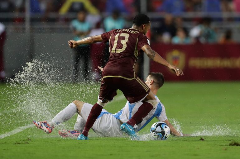 José Martínez (i) de Venezuela disputa un balón con Giovani Lo Celso de Argentina, en el empate 1-1 anoche en Maturín, donde el local sacó un punto ante el líder de las eliminatorias.