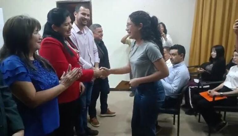 Una joven universitaria de la ciudad de Pilar recibe  el importe de la beca de la mano de Del Pilar Medina, coordinadora de acción social de la EBY.