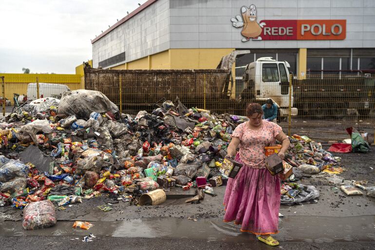 Una mujer recoge productos frente a un supermercado afectado por las inundaciones, en el municipio de São Leopoldo, en Rio Grande do Sul (Brasil).  La aparición de casos y al menos cinco muertes por leptospirosis, una enfermedad bacteriana comúnmente transmitida por las ratas, preocupa a las autoridades tras las inundaciones.