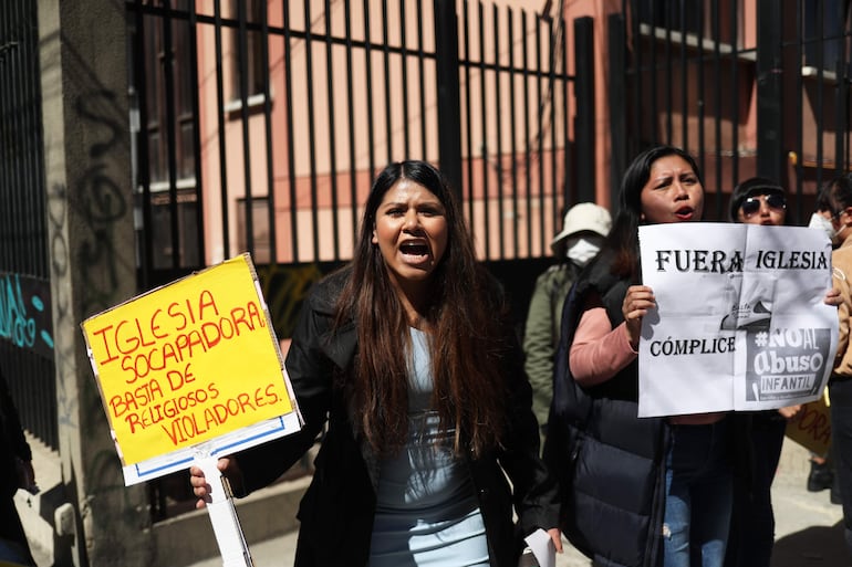 Varias personas protestan en contra de la Iglesia católica pegando carteles en las puertas del seminario San Jerónimo en La Paz (Bolivia). 