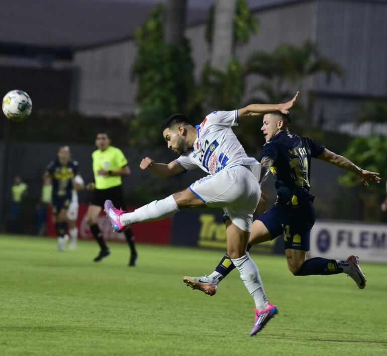 Leonardo Rivas despeja el balón sin dudar ante la llegada del jugador de Trinidense Milton Maciel.