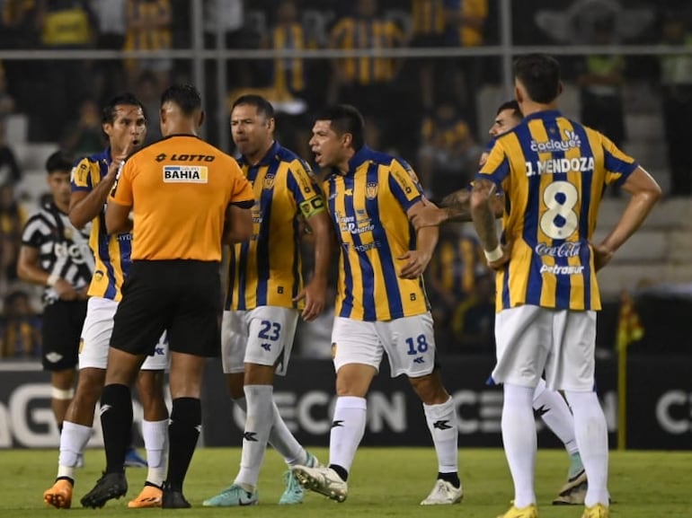 Los jugadores del Sportivo Luqueño reclaman al árbitro Blas Romero en un partido frente a Libertad por la segunda fecha del torneo Apertura 2024 del fútbol paraguayo en el estadio La Huerta, en Asunción.