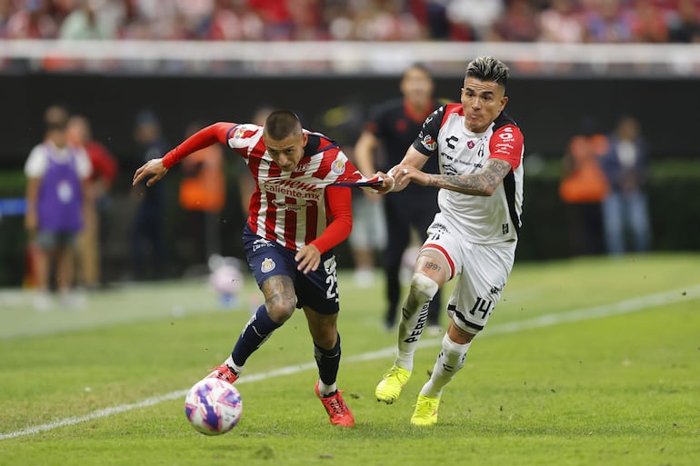 AME4943. GUADALAJARA (MÉXICO), 05/10/2024.- Roberto Alvarado (i) del Guadalajara disputa el balón con Luis Reyes (d) de Atlas este sábado, durante un partido del torneo apertura 2024 de la liga del fútbol mexicano en el Estadio Akron en la ciudad de Guadalajara, Jalisco (México). EFE/ Francisco Guasco
