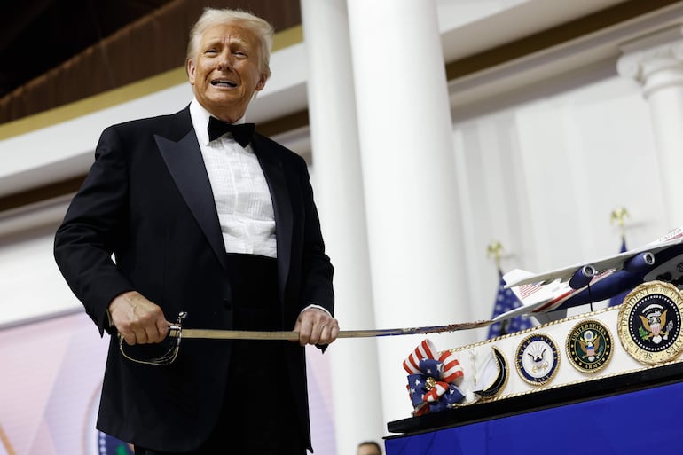 Donald Trump se prepara para cortar una torta con una espada.