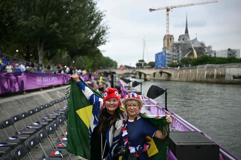 Los seguidores posan antes de la ceremonia de apertura de los Juegos Olímpicos de París 2024 en París el 26 de julio de 2024, mientras se ve la Catedral de Notre-Dame al fondo. 