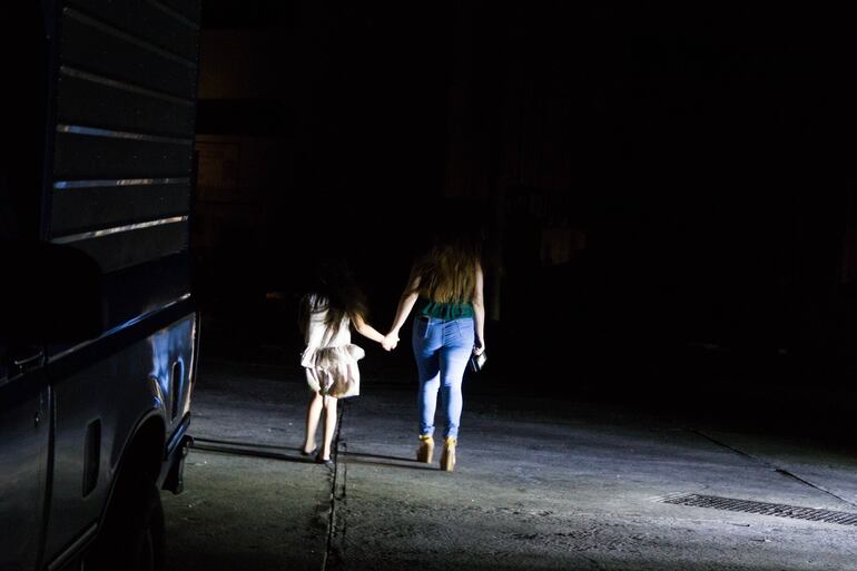 Una mujer y una niña caminan por la calle durante un apagón este lunes, en Maracaibo (Venezuela). Millones de venezolanos vuelven este lunes a vivir una noche de absoluta oscuridad debido a un apagón que ha afectado a casi todo el país sin que hasta ahora la estatal Corpoelec, que controla el servicio, ofrezca explicaciones al respecto.