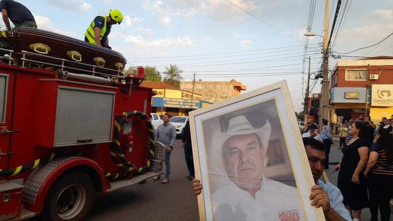 Un carro de bomberos transporta el cuerpo del cartista Eulalio "Lalo" Gomes por las calles de su ciudad, Pedro Juan Caballero. A su lado, un enorme retrato de Gomes. 