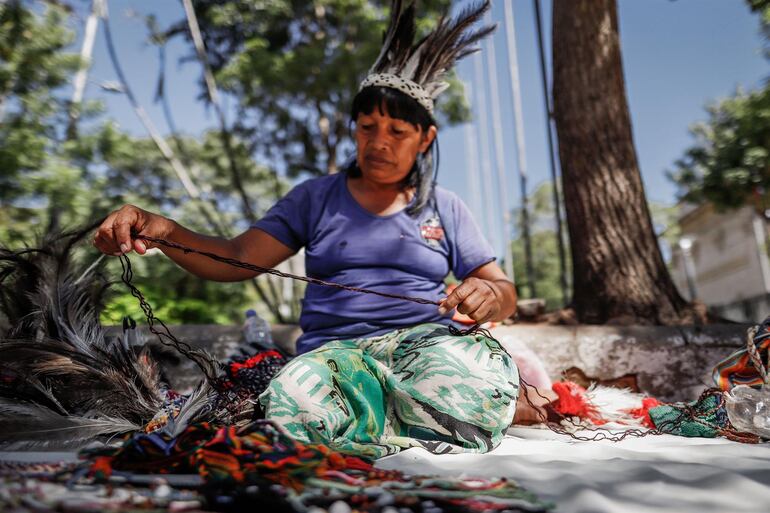 Una indígena Maká elabora una artesanía en Asunción.