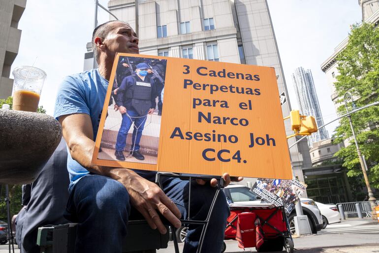 Un hombre sostiene una pancarta que pide "3 cadenas perpetuas al expresidente hondureño Juan Orlando Hernández" este miércoles, frente al tribunal federal de Manhattan en Nueva York (EE.UU.).  