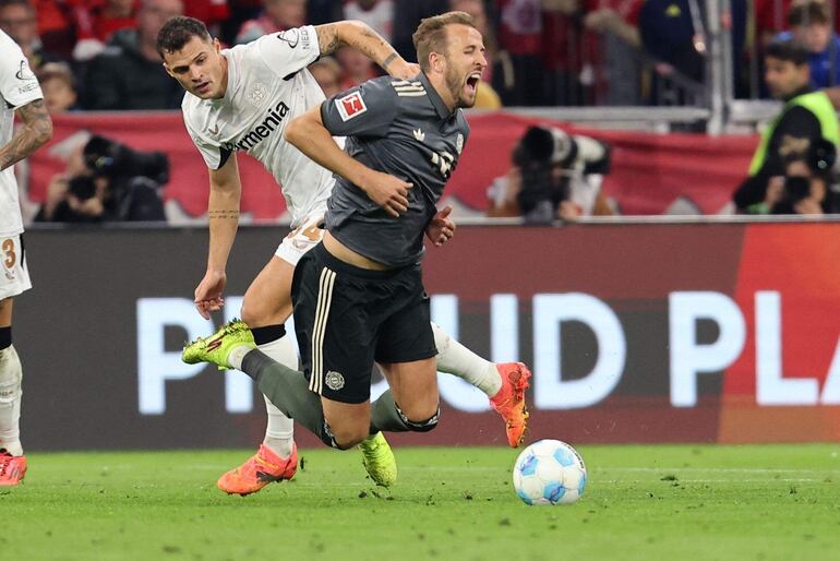 Bayern Munich's English forward #09 Harry Kane (R) reacts as he vies with Bayer Leverkusen's Swiss midfielder #34 Granit Xhaka during the German first division Bundesliga football match between FC Bayern Munich and Bayer 04 Leverkusen in Munich, southern Germany on September 28, 2024. (Photo by Alexandra BEIER / AFP) / DFL REGULATIONS PROHIBIT ANY USE OF PHOTOGRAPHS AS IMAGE SEQUENCES AND/OR QUASI-VIDEO