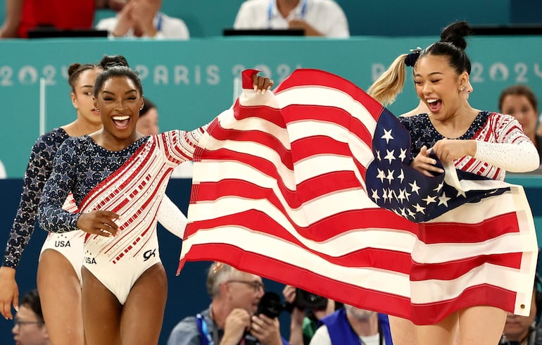 Simone Biles celebra con su equipo que vale oro.