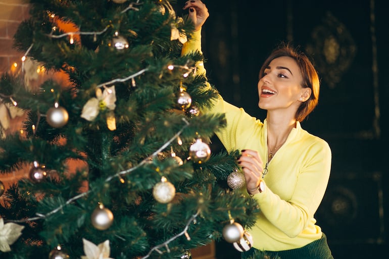 Imagen de una mujer decorando un árbol de Navidad.