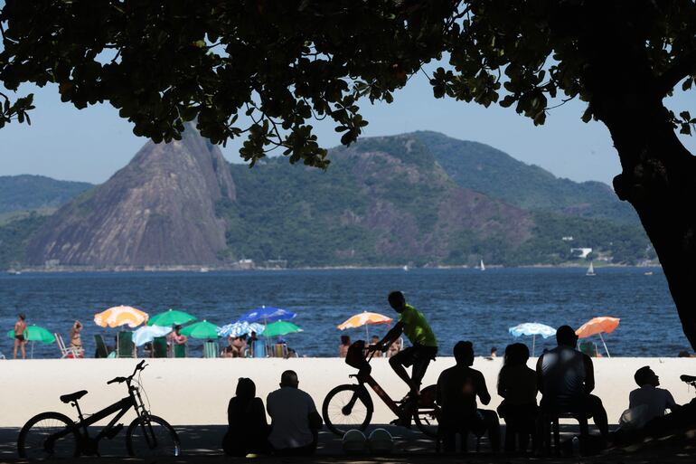 Personas disfrutan el día en la playa de Flamengo, en Río de Janeiro (Brasil). Quienes no tributen en Asunción, por estacionar de lunes a viernes sus autos, por ocho horas, deberán gastar en zonas controladas por Parxin, G. 6 millones al año. Con ese dinero ya podrían ir de vacaciones a Río.