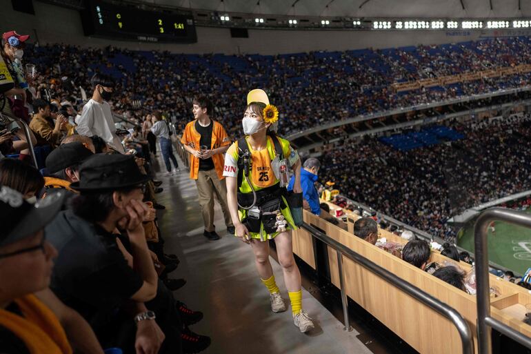 La vendedora de cerveza Honoka Hagiwara (centro) buscando clientes durante un partido de béisbol en el estadio Tokyo Dome en Tokio.