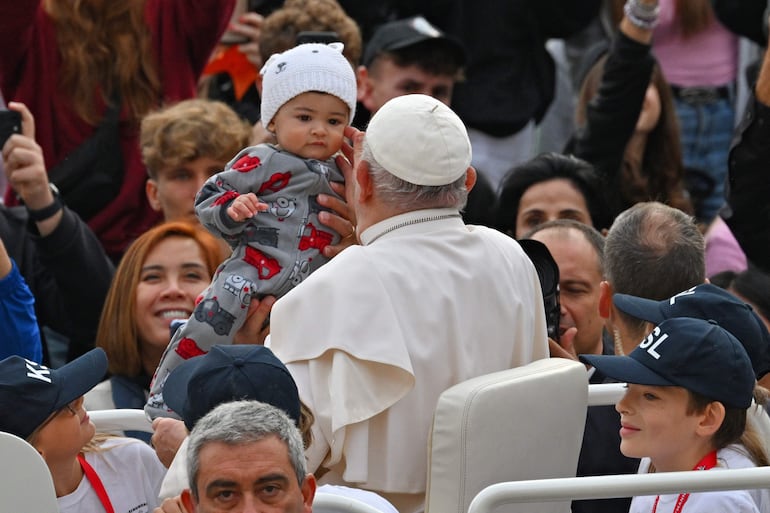 El papa Francisco acaricia del cachete de un niño.