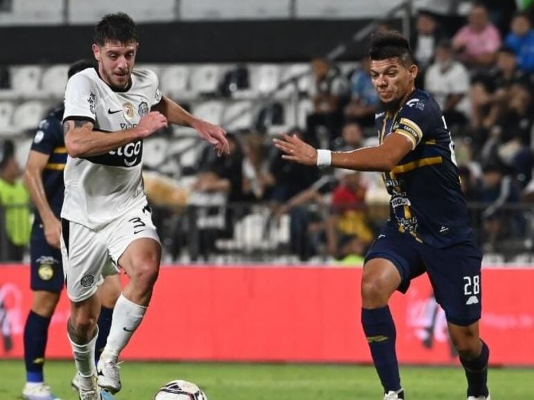 Marcos Riveros (d), futbolista de Sportivo Trinidense, pelea el balón con Alejandro Silva, jugador de Olimpia, en un partido por el fútbol paraguayo.