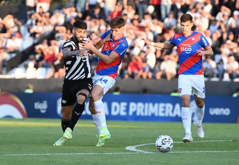 El argentino Alexander Barboza (i), jugador de Libertad, pelea por el balón en el partido contra Cerro Porteño por la ronda 19 del torneo Clausura 2023 del fútbol paraguayo.