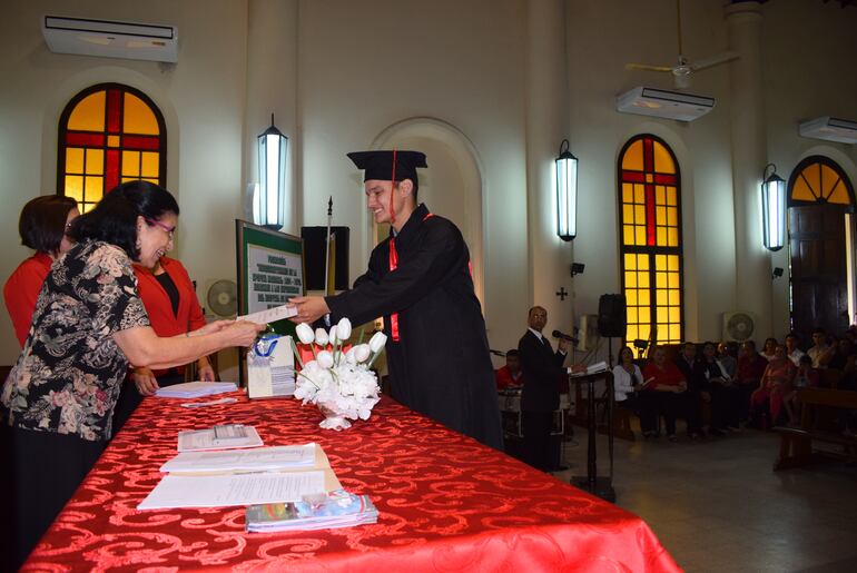 Madrina de la Promoción y ex directora del Instituto del Saber, Justina Ramírez de Ramírez, entrega el diploma a uno de los egresados.