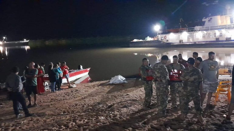 El cuerpo sin vida de Atanacio Arias Ayala tapado con una sábana blanca en la ribera del río Paraguay, tras ser rescatado en la zona de San Antonio.