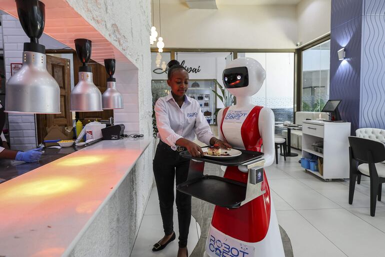 Una moza humana carga la bandeja con la orden que entregará la moza robot del Robot CafÈ de Kenia. 