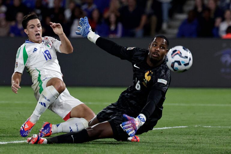 TOPSHOT - Italy's forward #18 Giacomo Raspadori scores his team third goal on front of France's goalkeeper #16 Mike Maignan during the UEFA Nations League Group A2 football match between France and Italy at the Parc des Princes in Paris on September 6, 2024. (Photo by STEPHANE DE SAKUTIN / AFP)