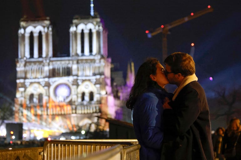 Una pareja se besa frente a la Catedral de Notre Dame, la noche antes de su reapertura, en la cual estará presente Santiago Peña.