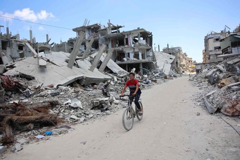 Un joven palestino cruza en bicicleta una zona afectada por bombardeos israelíes en Beit Lahia, en el norte de la Franja de Gaza, el lunes.