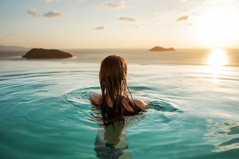 Mujer en una piscina natural al atardecer.