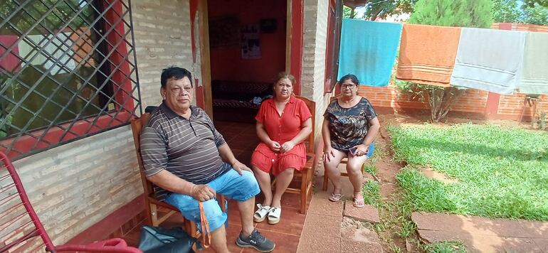 dos mujeres y un hombre sentados en su casa