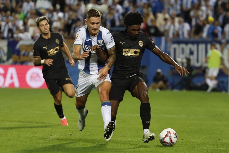 El defensa portugués del Valencia Thierry Rendall Correia (d) pelea un balón con Jorge Sáenz, del Leganés, durante el encuentro correspondiente a la jornada 9 de Laliga EA Sports que disputan hoy viernes CD Leganés y Valencia CF en el estadio de Butarque.