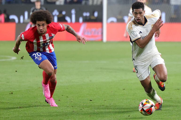 El inglés Jude Bellingham (d), del Real Madrid, domina el balón ante el acoso del belga Axel Witsel, del Atlético Madrid, durante el partido disputado ayer en Riad.