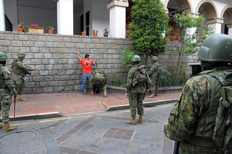 Soldados ecuatorianos cachean a un hombre mientras patrullaba por las calles de Cuenca, Ecuador, el 9 de enero de 2024, un día después de que el presidente ecuatoriano Daniel Noboa declarara el estado de emergencia tras la fuga de prisión de un peligroso jefe narco.